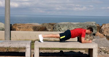 man doing plank exercise on the beach