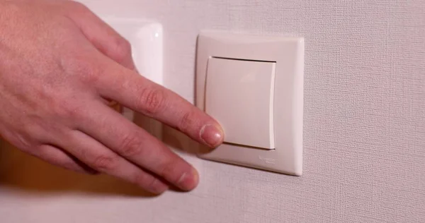 close-up view of man turning light switch off