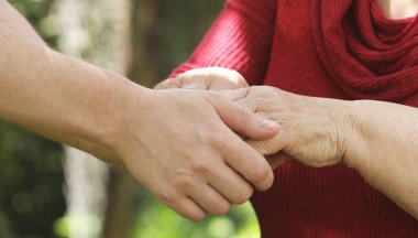close up of young and senior people holding hands together
