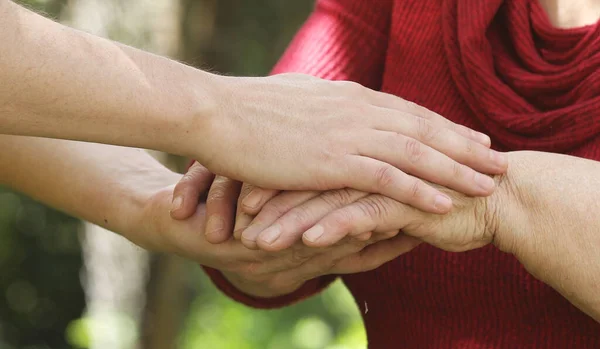 close up of young and senior people holding hands together