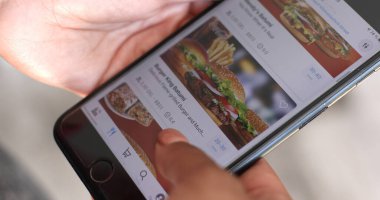 Batumi, Gürcistan - 10 Mayıs 2022: Cep telefonu uygulamasını kullanan kişi, kapat. Çevrimiçi Teslimat Restoranı ile Eller ve Akıllı Telefon Ekranı.