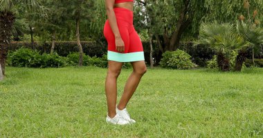 Genç bir kadın spor giyim reyonunda direniş gruplarıyla çalışıyor. Lastik spor kemeri olan bir spor eğitmeni.