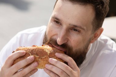 Caddedeki kafede hamburger yiyen genç adamın yakın plan görüntüsü, fast food.