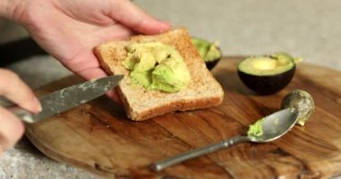 Avokado tostlu sağlıklı bir kahvaltı. Avokado tostu yapan kişi..
