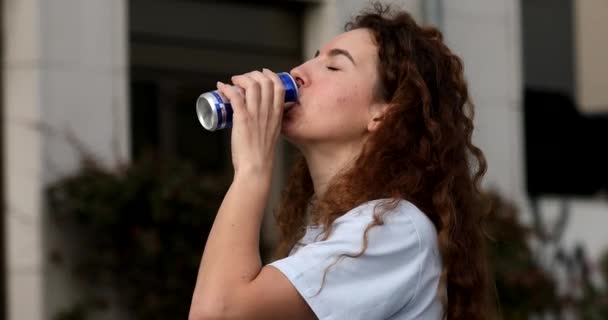 有魅力的年轻女子 一头长长的卷发 在户外喝能量饮料 — 图库视频影像