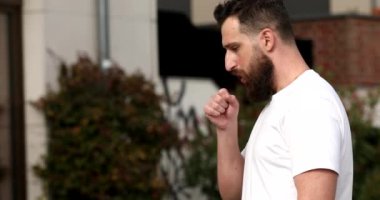 Sağlıksız, genç ve yakışıklı bir adam sabah sokakta yürüyor. Hasta adam öksürüyor ve hapşırma alerjisi var. - Soğuk. Grip oldum. Salgın.