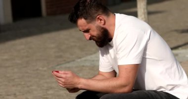 Dışarıda akıllı telefon kullanan yakışıklı beyaz bir adam.