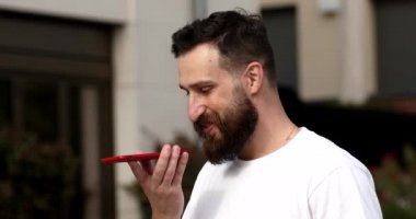 Sesli mesaj bırakan ya da cep telefonunda sanal asistan uygulaması kullanan bir adam. Genç adam sokakta yürürken hoparlörden sesli mesaj kaydediyor..