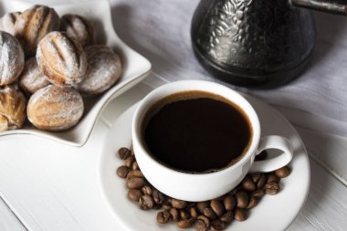 Kahvaltı için bir fincan sade kahve ve tatlı beyaz tahta bir masada.