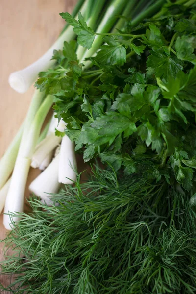 fresh herbs - dill, parsley and onion on a wooden table