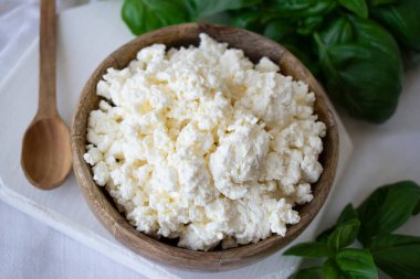 Kahvaltı için beyaz bir masada fesleğenli süzme peynir.