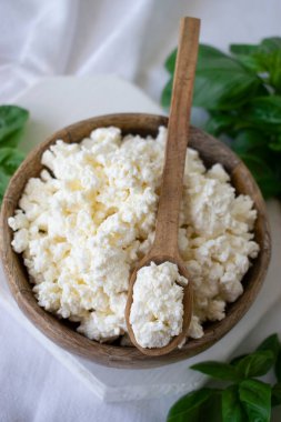 Kahvaltı için beyaz bir masada fesleğenli süzme peynir.