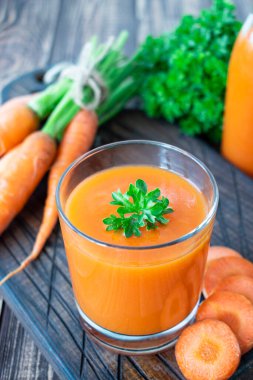 Taze havuç suyu ve bardaktaki bitkiler.