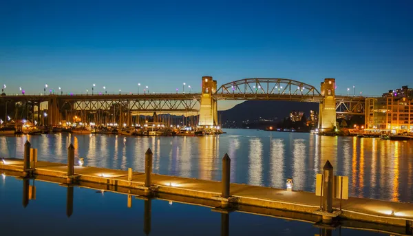 バンクーバーBcカナダ夜の偽クリーク沿いのグランヴィル橋 夕暮れ時のグランヴィル橋の夜景 川に夜間照明付きの木製の桟橋 ストリートビュー 旅行写真 — ストック写真