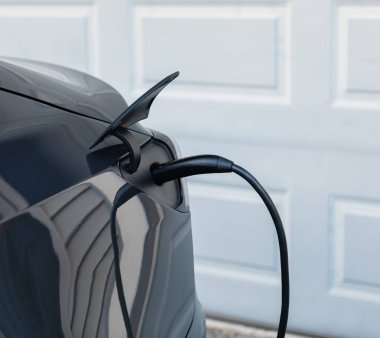 Şarj olan bir elektrikli arabaya takılan güç kaynağını kapatın. Elektrikli araba şarj istasyonu. Sokak görüntüsü, seçici odak