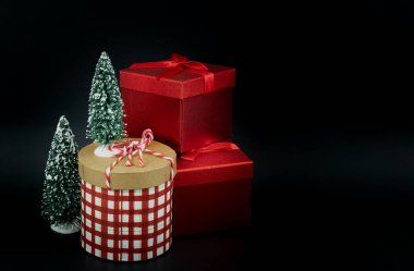 Karanlık arka planda Noel süslemesi olan hediye kutuları. Zarif hediye kutuları kırmızı ve beyaz çekler. Siyah arkaplan fotoğrafı, hiç kimse, metin için alanı kopyala