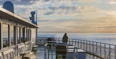 Feribotta durup denize bakan bir yolcu. Tekne açılırken turist. Genç bir kadın güvertenin kenarında dururken denize bakıyor.