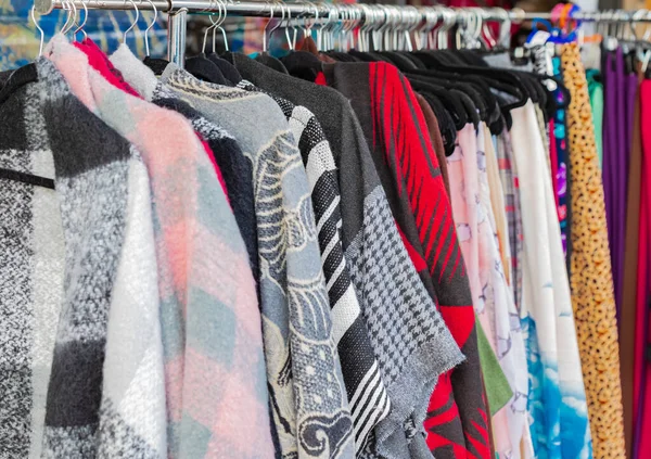 Dışarıdaki bir markette korkuluklara asılı giysiler. Bir sokak satıcısı tarafından satılacak renkli kıyafetler. Sokak fotoğrafı, seyahat fotoğrafı, kimse yok.
