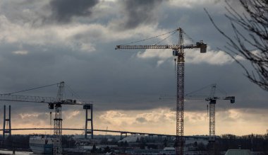 Dramatik bulutlu arka planda soyut vinçleri olan sanayi manzarası. New Westminster BC, Kanada-5 Aralık 2021 'de endüstriyel vinçleri olan bir yapı. Sokak görünümü.