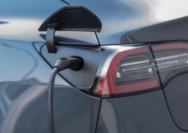 Şarj olan bir elektrikli arabaya takılan güç kaynağını kapatın. Elektrikli araba şarj istasyonu. Sokak görüntüsü, seçici odak