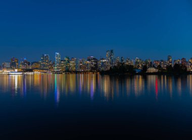 Vancouver 'ın gece ışıkları denize yansıyor. Gece Vancouver BC. Uzun pozlama, seyahat fotoğrafı, sokak manzarası. 13 Temmuz 2021-Vancouver, Kanada