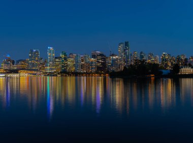 Vancouver 'ın gece ışıkları denize yansıyor. Gece Vancouver BC. Uzun pozlama, seyahat fotoğrafı, sokak manzarası. 13 Temmuz 2021-Vancouver, Kanada