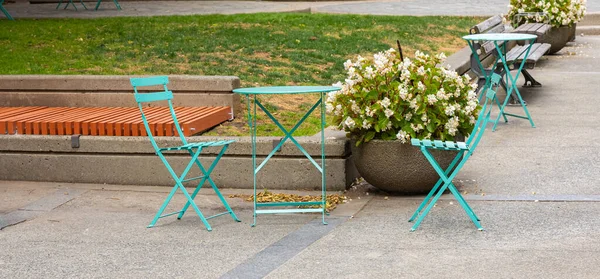 Set of folding wooden garden furniture table and chairs outdoor. Folding chair and table at a patio in summer day. Street photo, selective focus, nobody