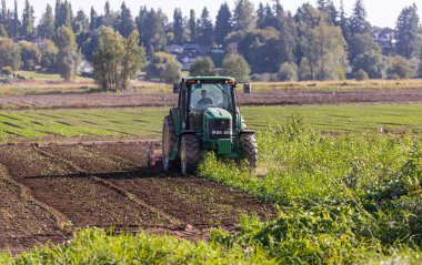 Traktör bahar ya da sonbahar mevsiminde tarlaları sürüyor. Sokak fotoğrafı, konsept fotoğraf tarımı, seçici odak noktası MÖ 1.2021-Vancouver, Kanada.