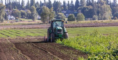Traktör bahar ya da sonbahar mevsiminde tarlaları sürüyor. Sokak fotoğrafı, konsept fotoğraf tarımı, seçici odak noktası MÖ 1.2021-Vancouver, Kanada.