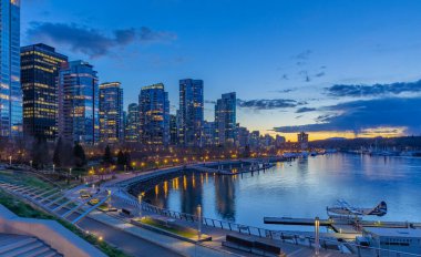 Vancouver şehir merkezindeki modern binaların gece manzarası. Vancouver Canada 'da uzun süre deniz kenarında görülmüş. Gökdelenlerle dolu renkli bir şehir gecesi. Sokak fotoğrafı, seçici odak noktası, gece fotoğrafı 11 Nisan 2022
