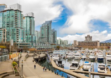 Vancouver 'daki Harbor' ın çarpıcı manzarasında şehir merkezindeki güzel binalar, tekneler var. Kanada 'nın başkenti Vancouver BC' de yaz günü, turistler gezinti güvertesinde yürüyorlar - 11 Nisan 2022