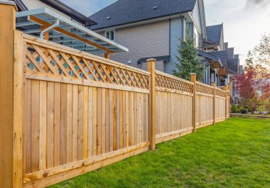 Evin etrafında güzel ahşap çitler var. Yeşil çimleri ve ağaçları olan ahşap çitler..