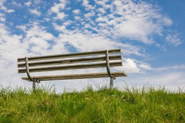 Parkta yeşil taze çimenleri olan boş bir bank. Mavi gökyüzü arka planında park bankında, cennette bir bank konsepti, dinlenmek için bir yer. Hiç kimse, seyahat fotoğrafı, metin için kopyalama alanı