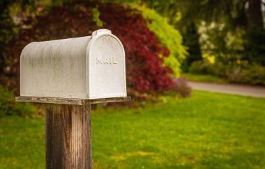 White mailbox in a rural setting in background. Communication concept. Retro style postbox at roadside. Street photo, nobody, selective focus