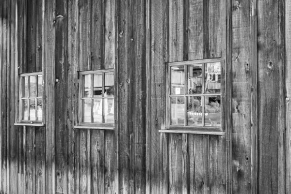 Ventanas en una pared de madera envejecida, fondo grungy abstracto. Muralla vieja descolorida con ventanas de un granero — Foto de Stock