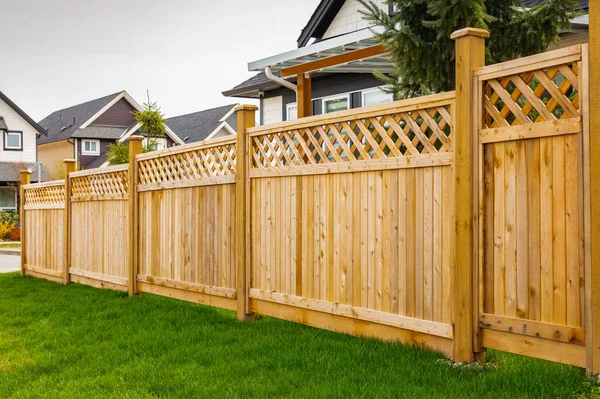 Pěkný dřevěný plot kolem domu. Dřevěný plot se zeleným trávníkem. — Stock fotografie