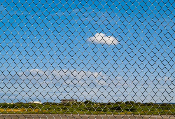 Fence with metal grid in perspective. Metal fence Part of a metal grid fence in blue sky at the background. Street view, depth of feild, nobody