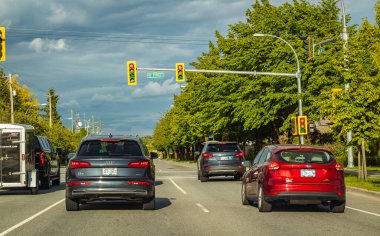 Yaz bulutlu bir günde şehir yolunda arabalar hareket eder. British Columbia Kanada 'da bir otoyolda trafik ışığı. Seyahat fotoğrafı, seçici odak, sokak manzarası - 29 Mayıs 2022-Delta BC.