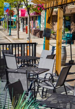 Masaları ve sandalyeleri olan boş bir restoran yaz terası. Yaya caddesindeki kafe terasında. Dışarıdaki terasta müşterileri bekleyen restoran masaları. Sokak manzarası, seyahat fotoğrafı, kimse yok.