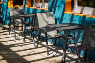 Masaları ve sandalyeleri olan boş bir restoran yaz terası. Yaya caddesindeki kafe terasında. Dışarıdaki terasta müşterileri bekleyen restoran masaları. Sokak manzarası, seyahat fotoğrafı, kimse yok.
