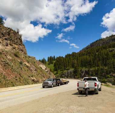 Broke Down arabasının yanında yardım bekleyen bir kadın. Keremeos British Columbia Canada 'daki Mountan karayolundaki kamyonlar. Seyahat fotoğrafı - 6 Haziran 2022