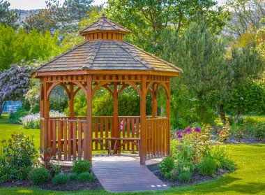 Güzel yeşil bir bahçedeki ahşap pergola. Sokak fotoğrafı, hiç kimse, seçici odaklanma. Güzel çardak.