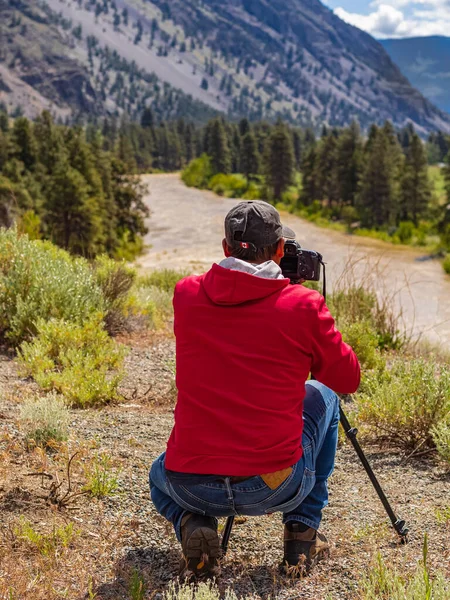 Man photographer taking photographs with digital camera in a mountains. Travel and active lifestyle concept. Creative photographing. Photographer taking photo in Canadian National Park-June 6,2022