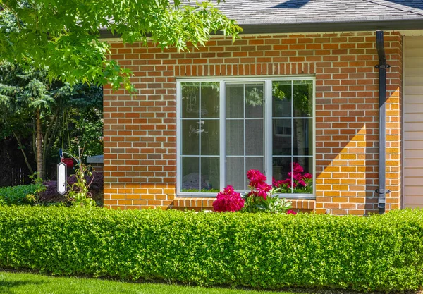 Facade with window of a brick house with a patio on a bright sunny day in Vancouver Canada. Facade of residential home. A house with sunlit exterior. House front door. Nobody-June 24,2022