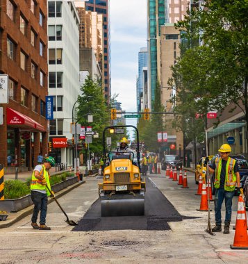 İşçiler, sıcak asfaltı yola koydular. Koruyucu üniformalı küreklerle yol inşaat işçileri. 10 Temmuz 2022-Vancouver Kanada 'da Road İnşaat İşletmeleri. Sokak fotoğrafı