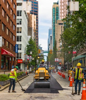 İşçiler, sıcak asfaltı yola koydular. Koruyucu üniformalı küreklerle yol inşaat işçileri. 10 Temmuz 2022-Vancouver Kanada 'da Road İnşaat İşletmeleri. Sokak fotoğrafı