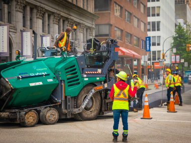 İşçiler, sıcak asfaltı yola koydular. Koruyucu üniformalı küreklerle yol inşaat işçileri. 10 Temmuz 2022-Vancouver Kanada 'da Road İnşaat İşletmeleri. Sokak fotoğrafı