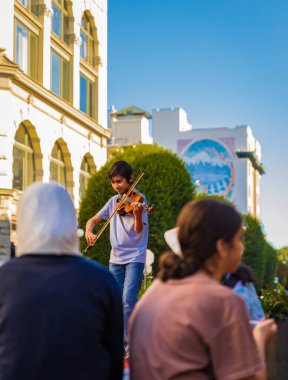 Keman çalan müzisyen. Şehir caddesinde ara sokakta keman çalan çocuk. Enstrümanlı küçük müzisyen portresi. Seyahat fotoğrafı - 19 Temmuz 2022 - MÖ Victoria Kanada