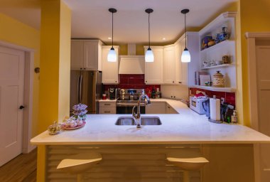 Ada, kolye ışıkları, dolapları olan lüks bir evde güzel bir mutfak. Fayansız su sıçratma, paslanmaz çelik fırın, menzil ve kaput iltifat zarif özellikler - 18 Temmuz 2022 - Victoria BC Kanada-Hiç Kimse