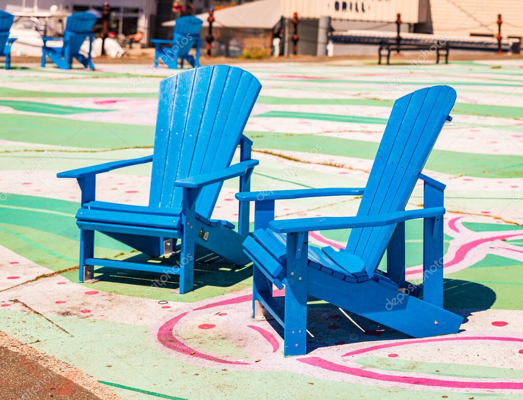 Two wooden adirondack chairs. Blue adirondack chairs on the street. Travel photo, nobody